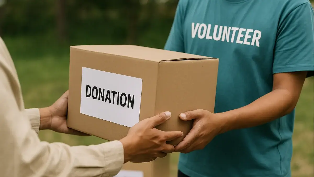 Seorang relawan dengan kaos bertuliskan "VOLUNTEER" menyerahkan kotak kardus bertuliskan "DONATION" kepada tangan lain, mewakili etika donasi yang berpusat pada kejujuran dan tanggung jawab dalam proses pemberian bantuan.